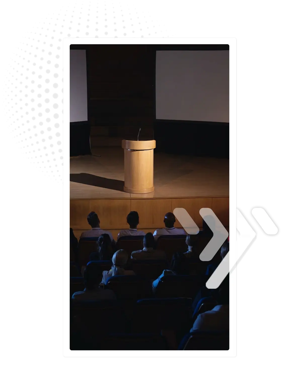 An empty lectern on stage in front of a seated audience