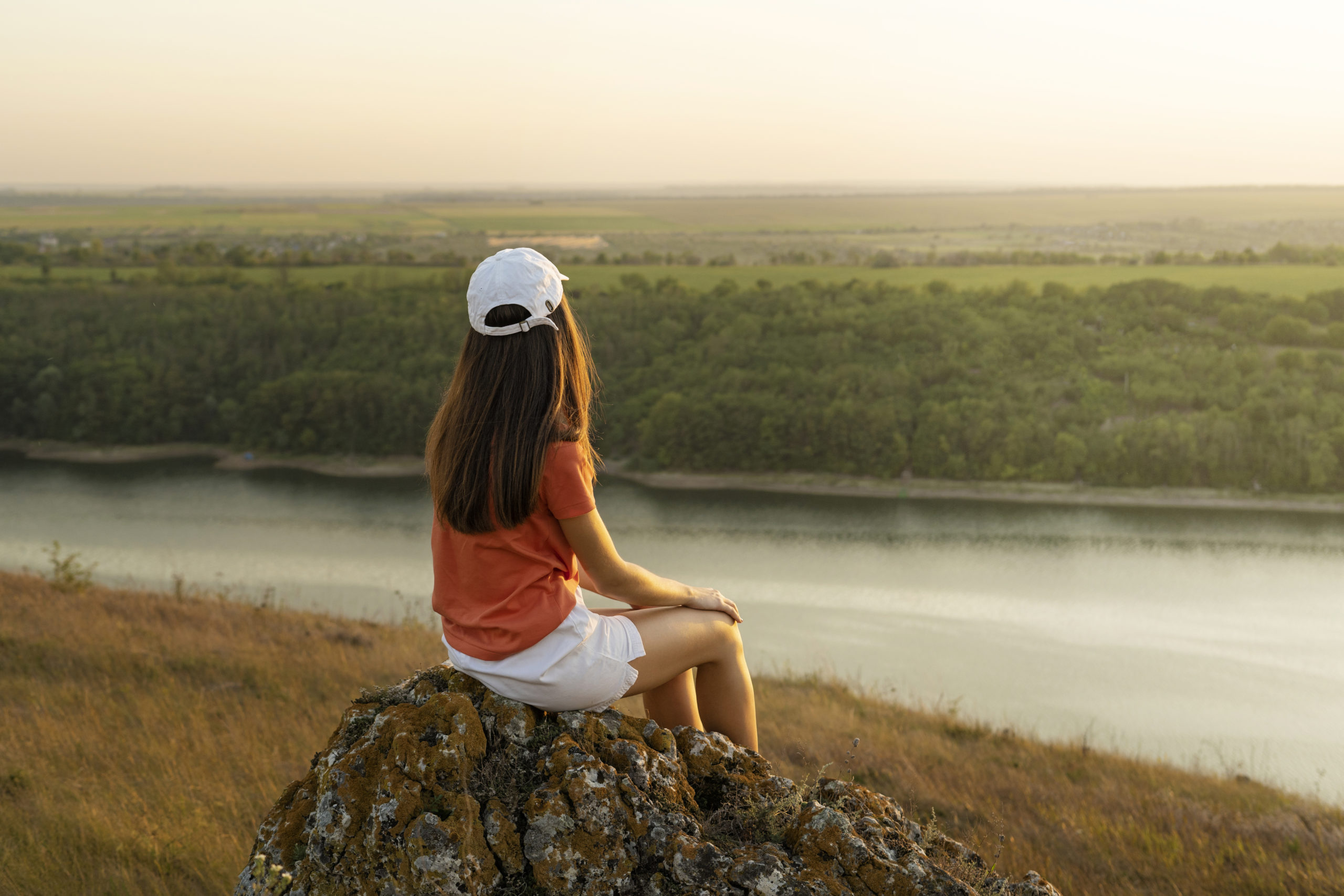 Person standing by a calm lake at sunrise, reflecting inner peace and mental clarity, symbolising healing from anxiety, depression, and trauma.